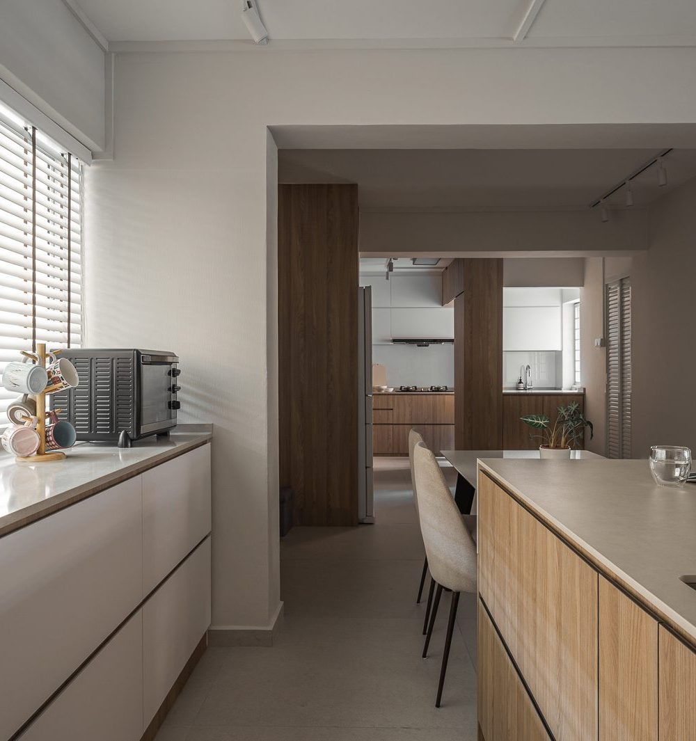 Morning light spills across the counter, styled simply with a mug stand and toaster oven, with the second kitchen zone visible beyond.