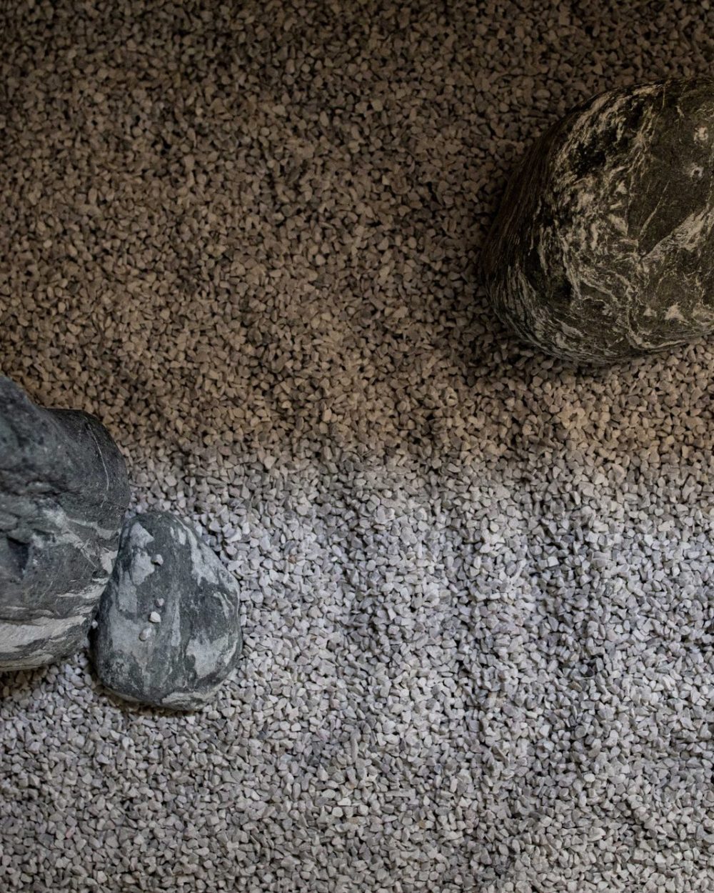 Layered stones sit within contrasting bands of grey and beige gravel, raked into soft curving lines.