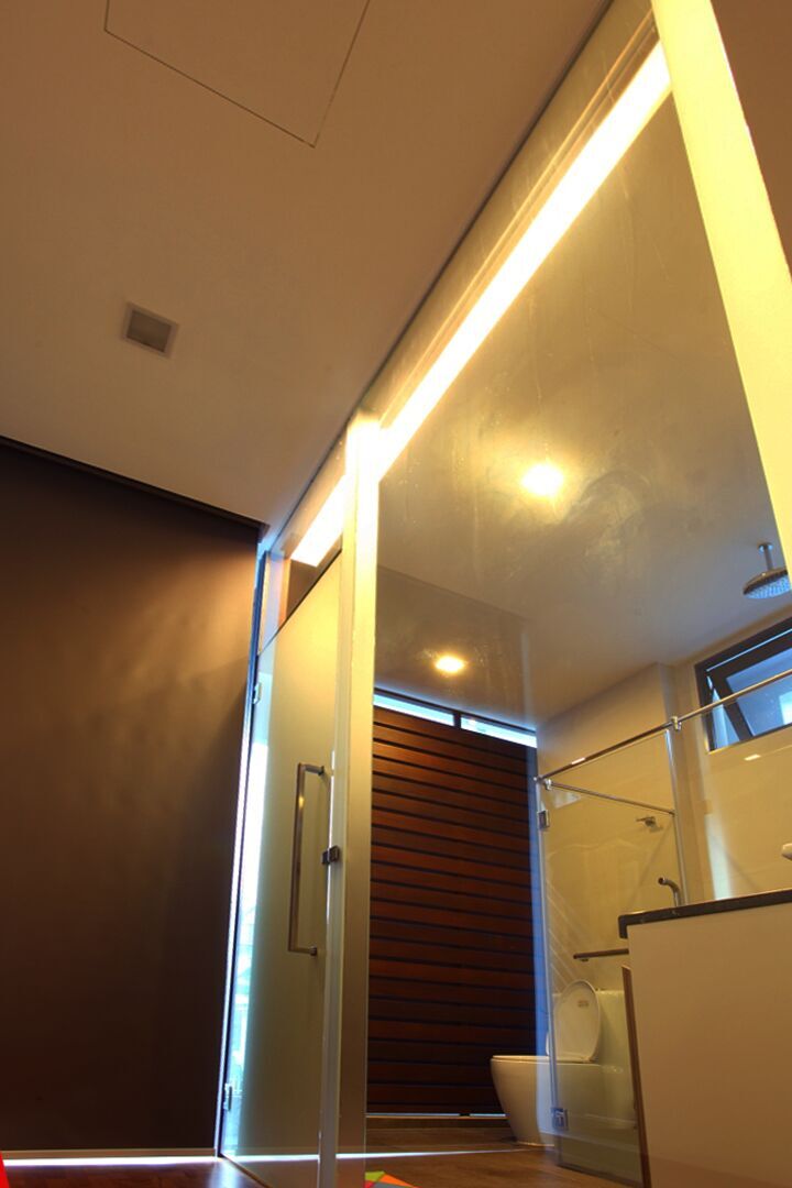 A timber slat door and glass shower enclosure give this ensuite bathroom a warm, spa-like entrance.