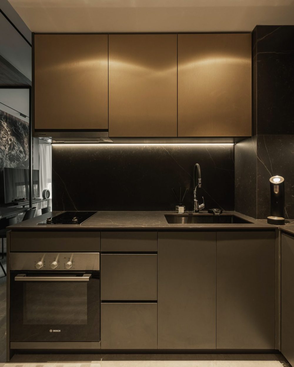 Vertical timber slats frame a round backlit mirror above a black oval vessel sink and dark marble counter.