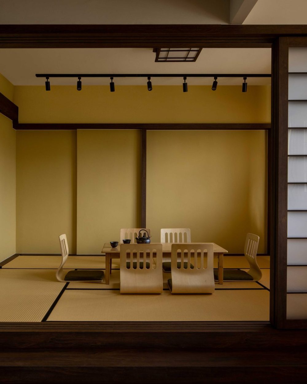 A tatami-matted tea room sits behind sliding shoji screens, furnished with low legless chairs and a solid wood table for entertaining.