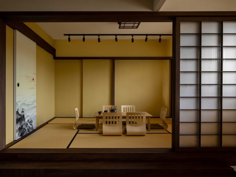 A tatami-matted tea room sits behind sliding shoji screens, furnished with low legless chairs and a solid wood table for entertaining.