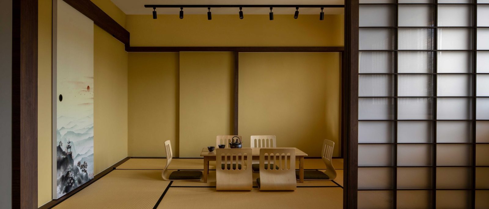 A tatami-matted tea room sits behind sliding shoji screens, furnished with low legless chairs and a solid wood table for entertaining.