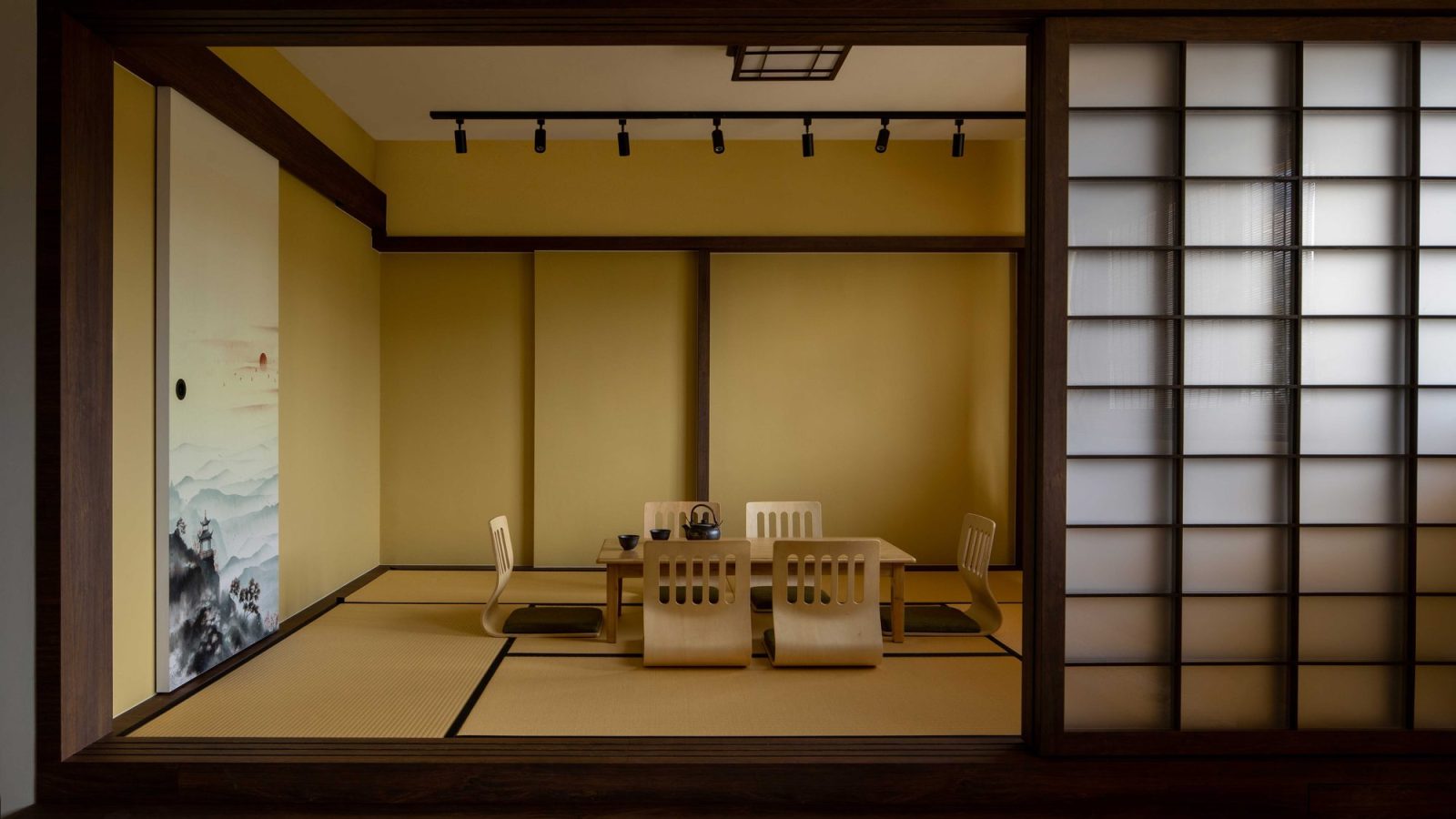 A tatami-matted tea room sits behind sliding shoji screens, furnished with low legless chairs and a solid wood table for entertaining.