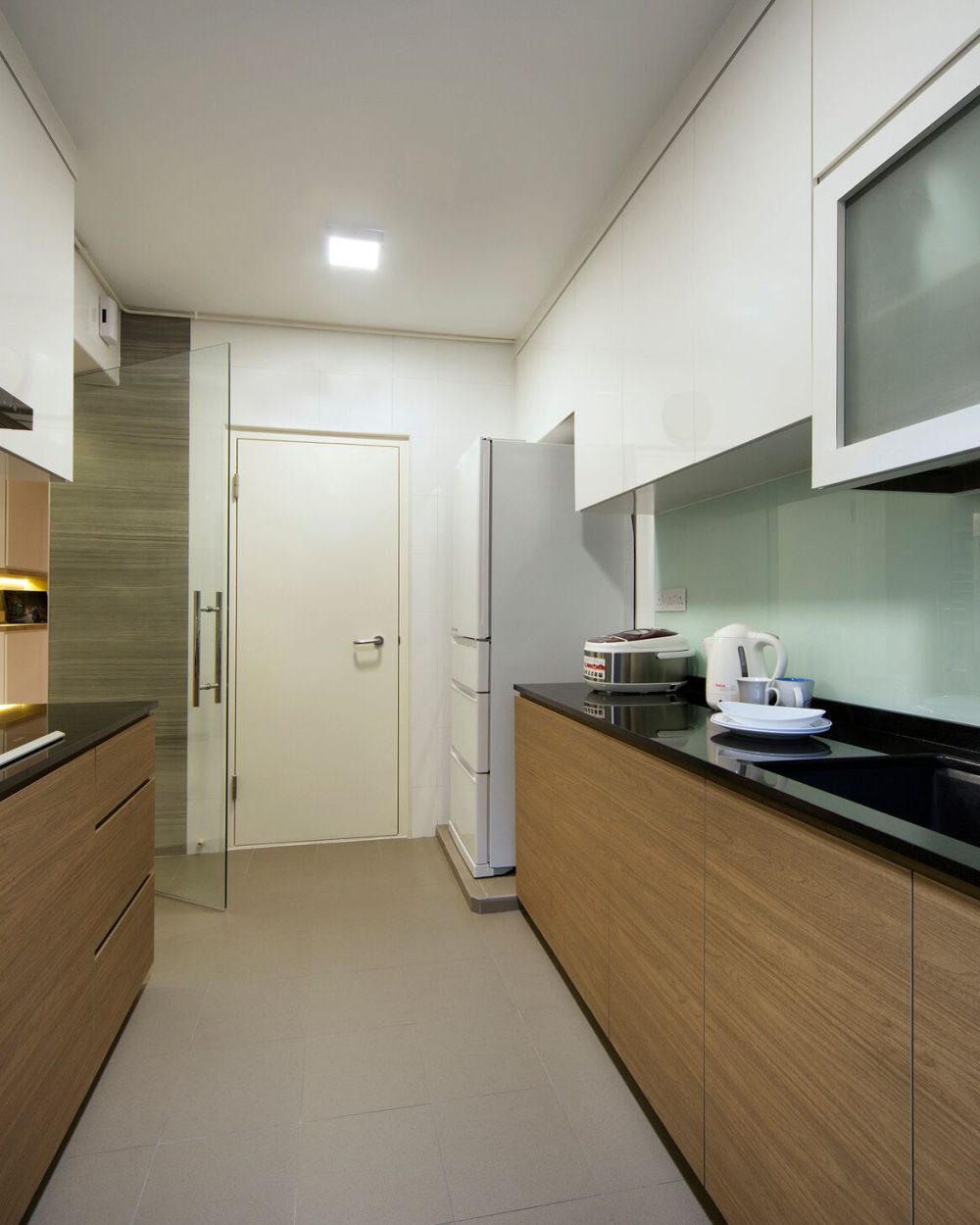 White gloss upper cabinets meet warm timber-toned lower units and a black stone counter, finished with a glass splashback and frosted glass door.