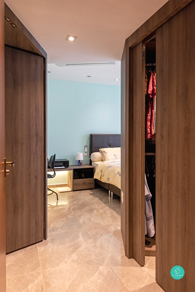 A sliding timber door opens from the bedroom into a walk-in wardrobe, with a study desk and soft mint-toned wall visible beyond.