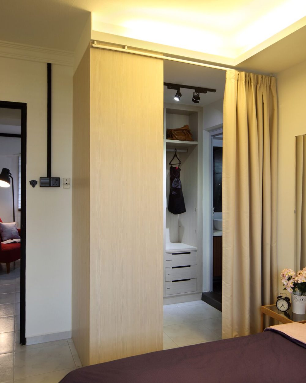 The master bedroom opens into a curtained walk-in wardrobe with open shelving and drawers, leading through to its own ensuite bathroom.