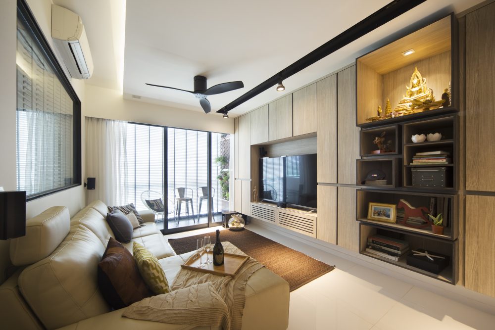 A cream leather sofa and black ceiling fan sit opposite a floor-to-ceiling display wall, with a dedicated gold Buddha altar niche built into the joine
