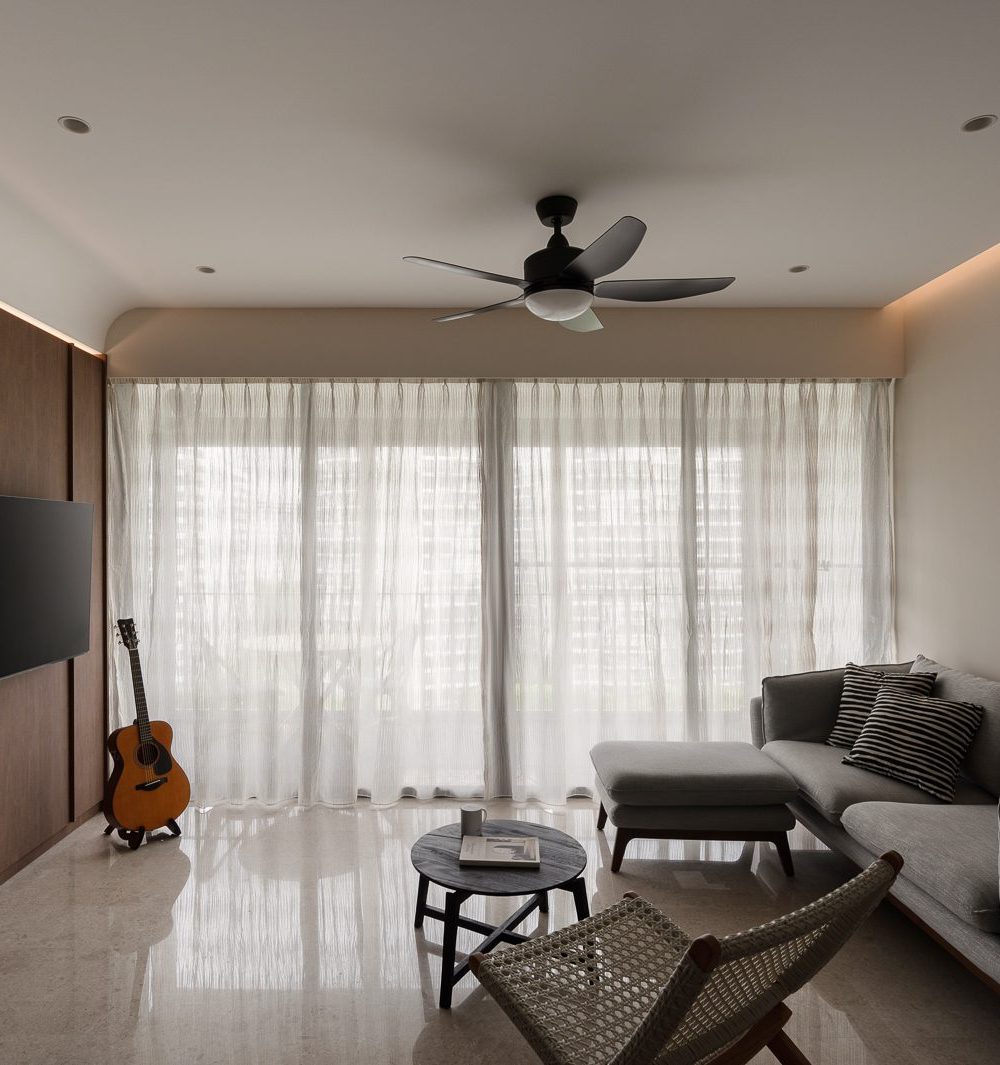 A full-height timber panel wall with cove lighting anchors the living room, paired with a grey sectional sofa and sheer curtains.