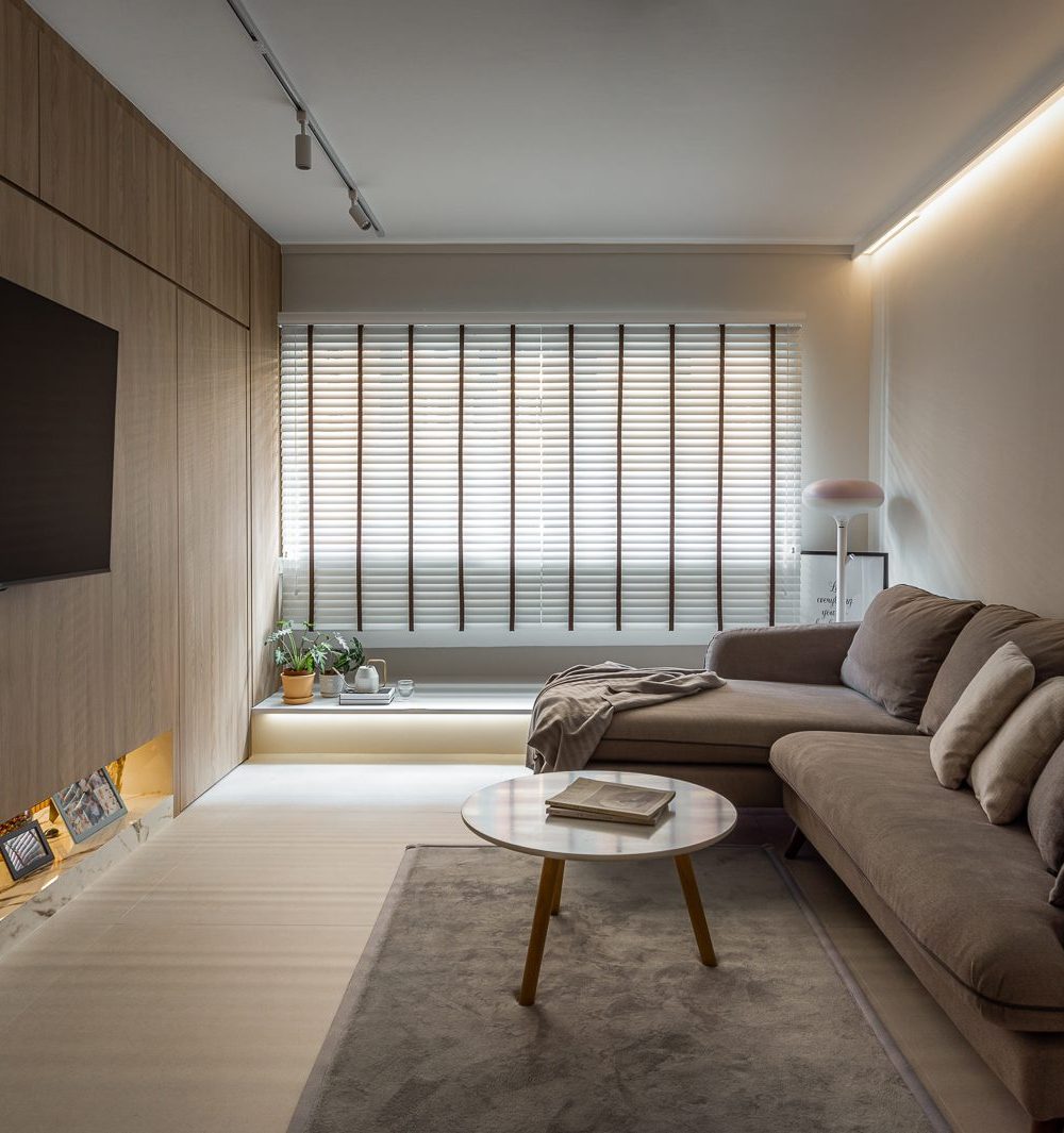 Full-height timber panelling wraps the TV wall, with a backlit marble ledge below for photos and keepsakes, beside a plush sectional sofa.
