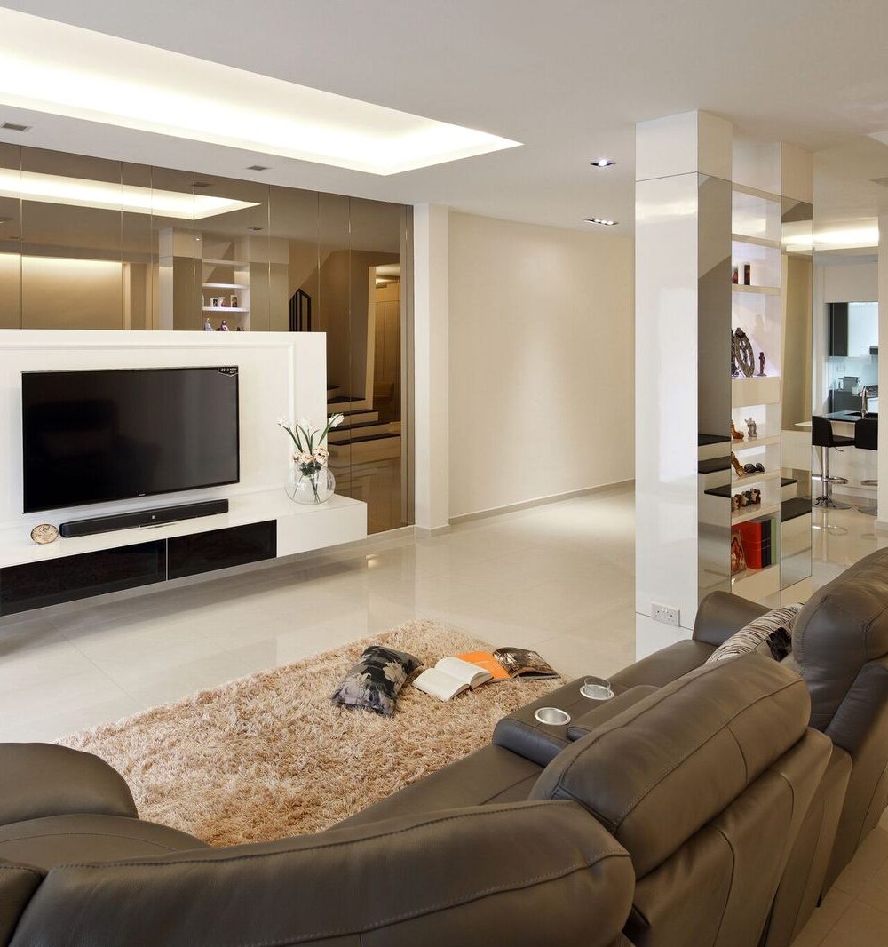 Classic white wall panelling frames a second TV wall, with a mirrored surface extending the room visually toward the hallway.