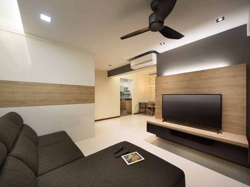 A slatted charcoal-grey and oak-toned wall anchors the TV, with a striped feature wall in the adjoining nook and a wood-panelled dining area beyond.